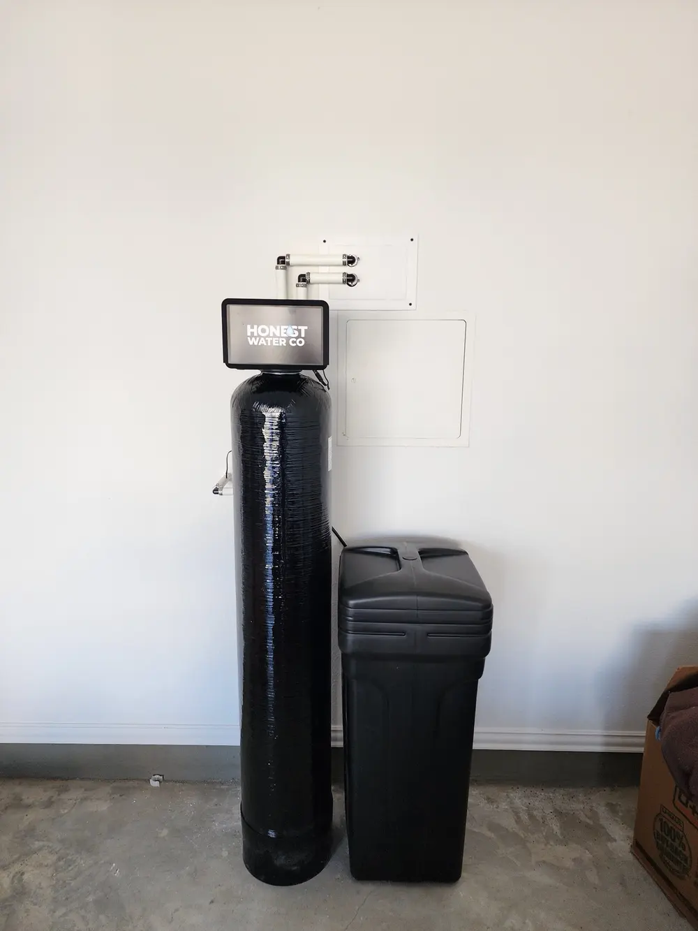 Single-tank Honest Water Co softener beside its brine tank in a garage