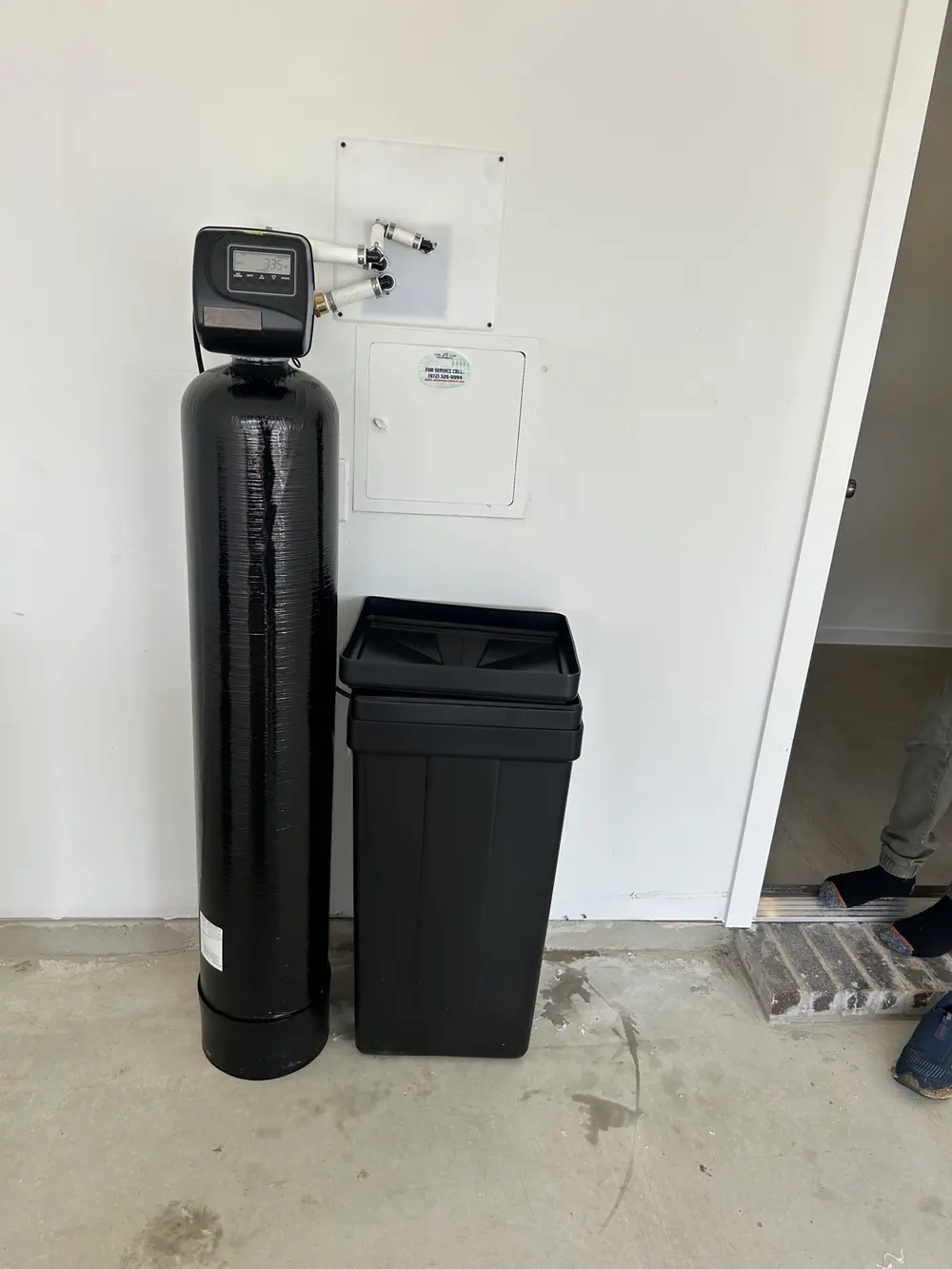Metered softener and brine tank installed against a garage wall