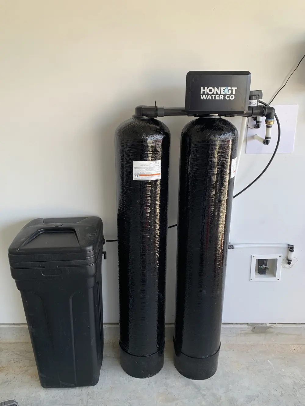 Dual-tank Honest Water Co softener and brine tank mounted along a garage wall